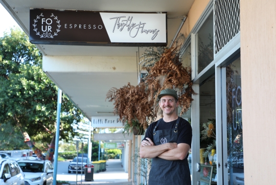 Man smiling with crossed arms infront of store